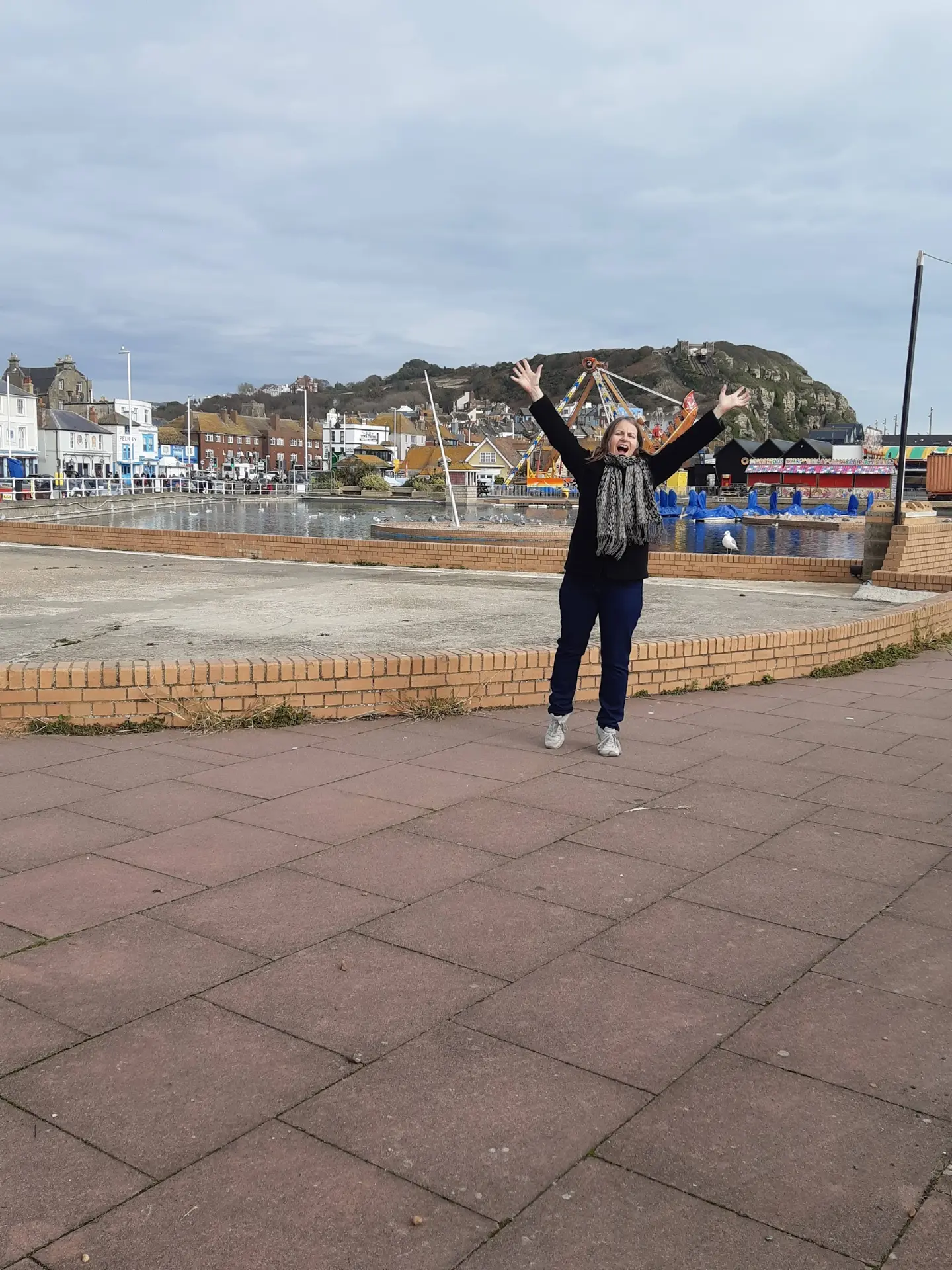 Nicky celebrating with arms raised by the seafront
